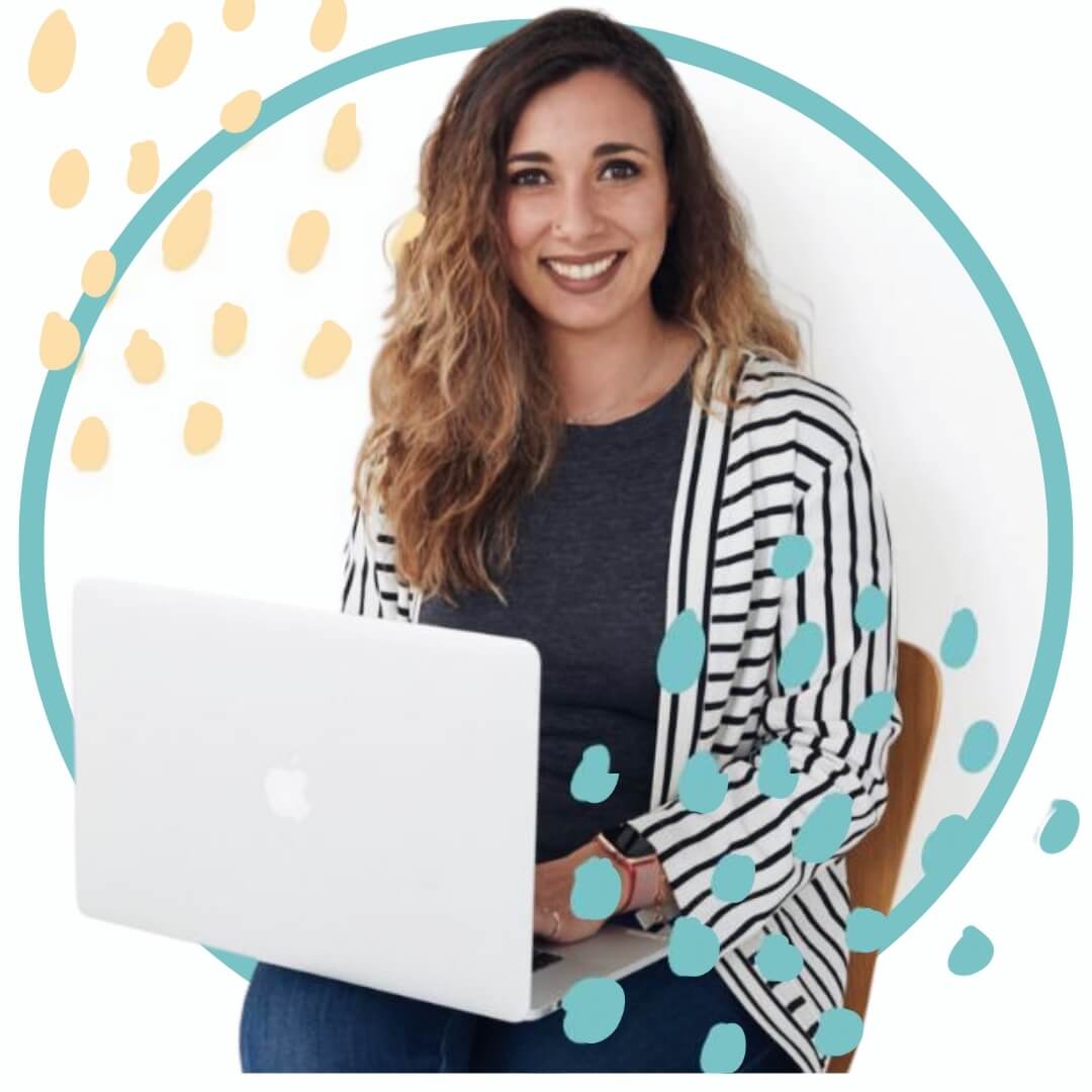 coaching Una mujer con cabello largo y ondulado sonríe a la cámara mientras está sentada y usa una computadora portátil. Está vestida con una camisa oscura y un cárdigan a rayas. El fondo tiene una superposición gráfica circular con detalles de puntos amarillos y azules. spiritual mood